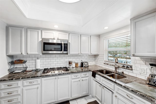 kitchen with sink, a raised ceiling, white cabinets, and appliances with stainless steel finishes