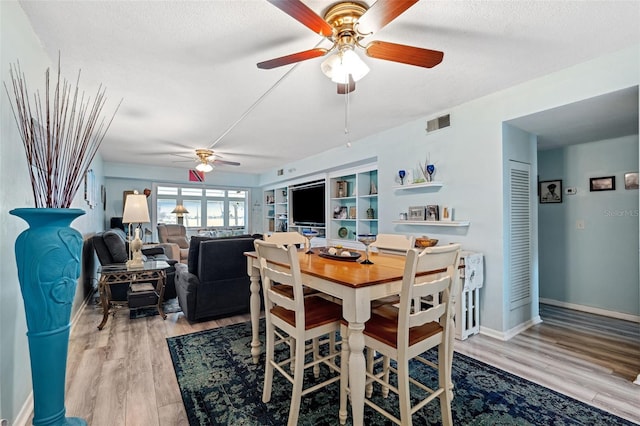 dining space with ceiling fan, a textured ceiling, and light wood-type flooring