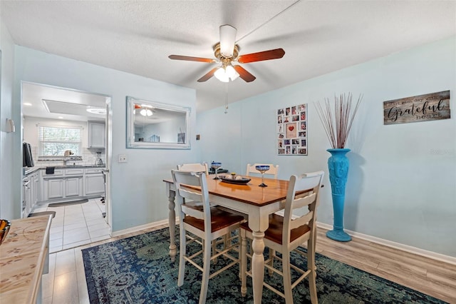 dining area with light wood-type flooring, a textured ceiling, and ceiling fan