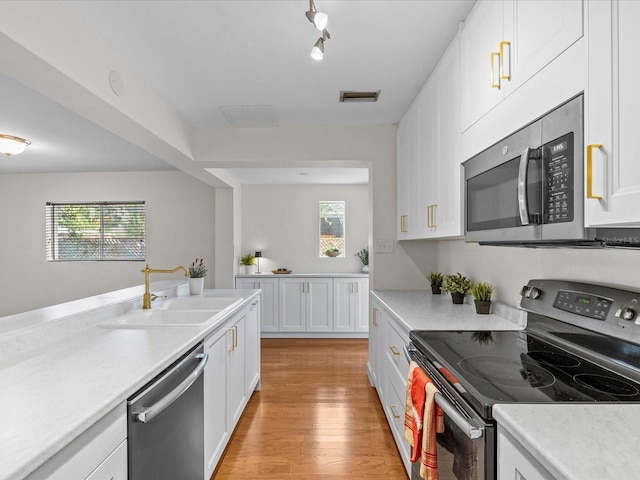 kitchen with white cabinetry, stainless steel appliances, light hardwood / wood-style floors, and sink