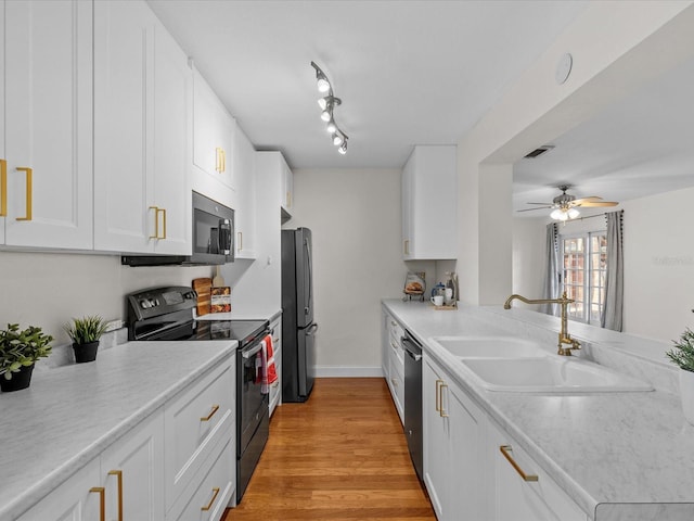 kitchen featuring sink, white cabinets, ceiling fan, black appliances, and light hardwood / wood-style flooring