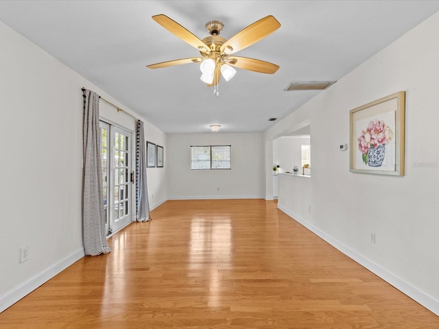 empty room with french doors, ceiling fan, and light hardwood / wood-style flooring