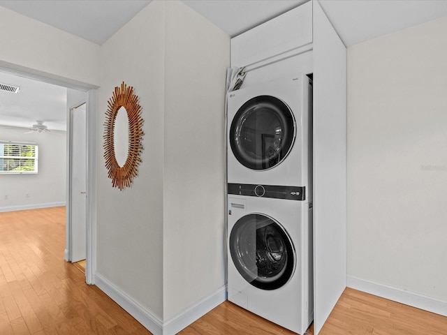 laundry room featuring stacked washer / dryer and light hardwood / wood-style flooring