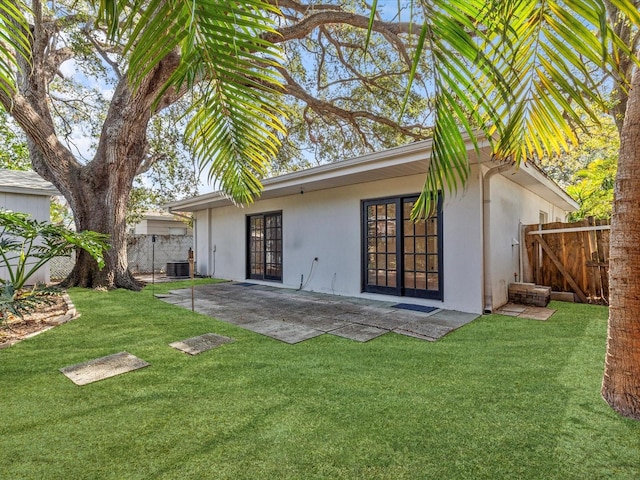 rear view of house featuring cooling unit, a patio, a lawn, and french doors