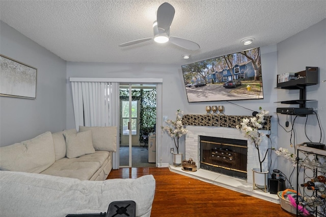 living room featuring hardwood / wood-style flooring, ceiling fan, and a textured ceiling