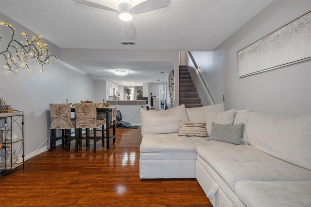 living room featuring dark hardwood / wood-style flooring, ceiling fan, and a textured ceiling