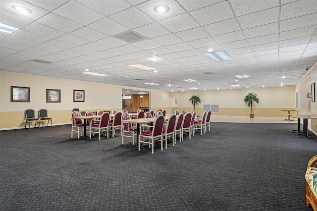 dining room with a paneled ceiling and dark colored carpet