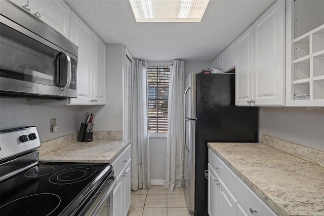 kitchen featuring light tile patterned flooring, appliances with stainless steel finishes, a textured ceiling, and white cabinets