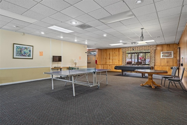 rec room featuring wood walls and dark colored carpet