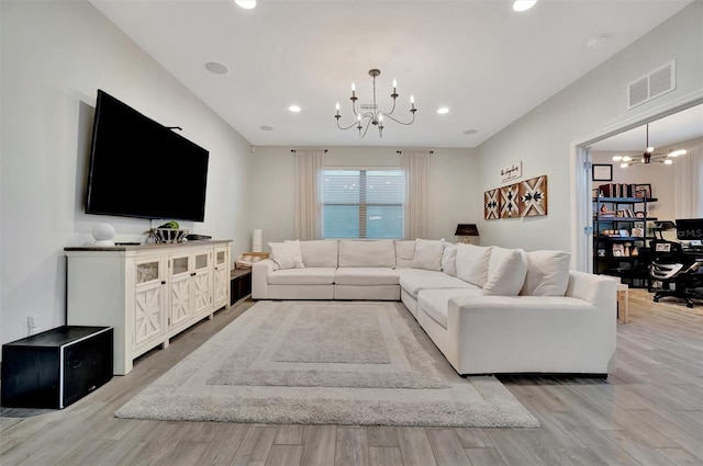 living room with light hardwood / wood-style floors and a notable chandelier