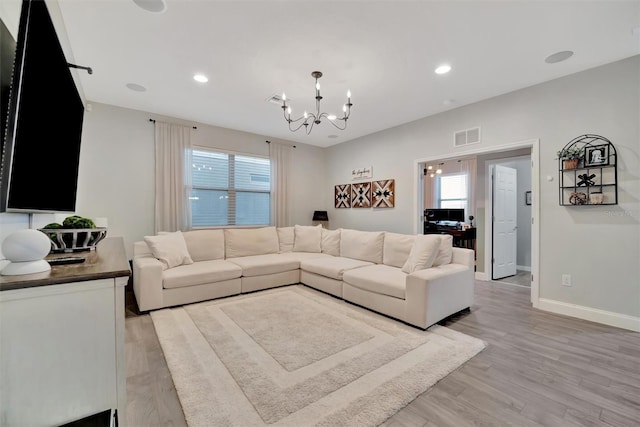 living room with light hardwood / wood-style floors and a notable chandelier