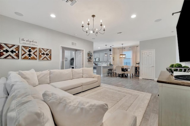 living room with light wood-type flooring and a chandelier