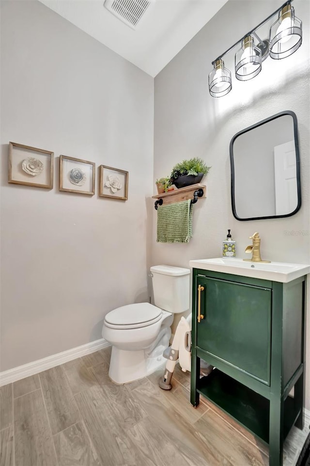 bathroom with hardwood / wood-style flooring, lofted ceiling, vanity, and toilet