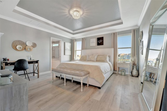 bedroom featuring crown molding, connected bathroom, a raised ceiling, and light wood-type flooring