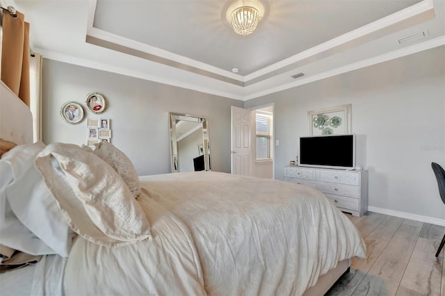 bedroom with crown molding, a raised ceiling, and light wood-type flooring