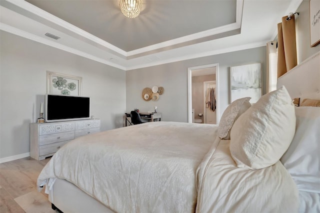 bedroom with crown molding, a tray ceiling, and light wood-type flooring