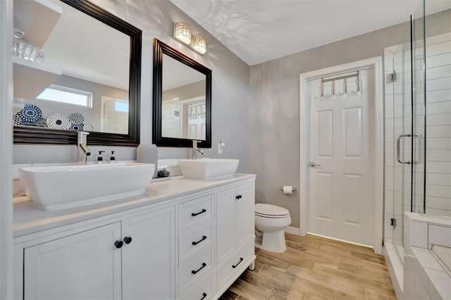 bathroom featuring hardwood / wood-style flooring, vanity, toilet, and a shower with door