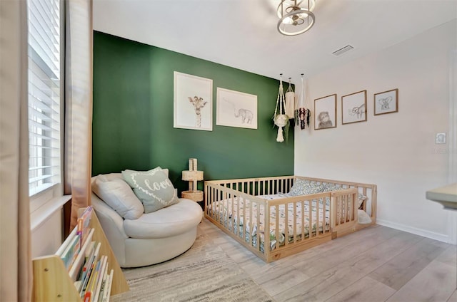 bedroom with a nursery area and light hardwood / wood-style floors