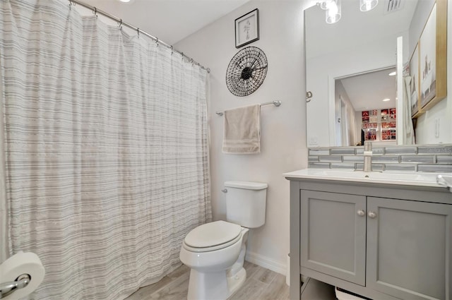 bathroom with hardwood / wood-style flooring, vanity, toilet, and walk in shower