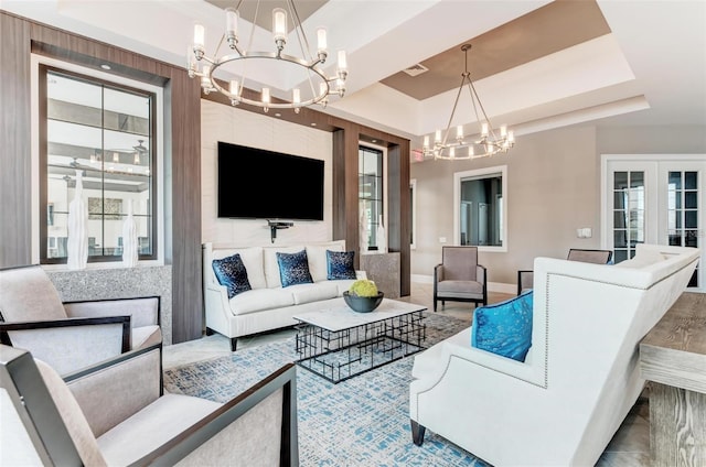 living room featuring french doors, a tray ceiling, hardwood / wood-style floors, and a notable chandelier