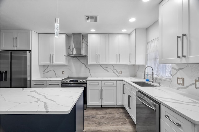 kitchen featuring decorative light fixtures, white cabinetry, stainless steel appliances, light stone countertops, and wall chimney exhaust hood