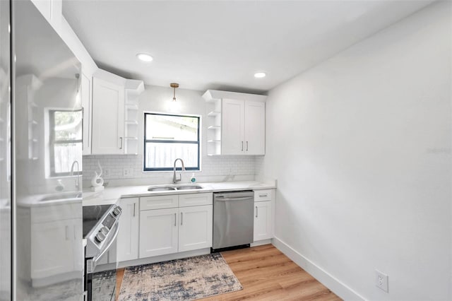 kitchen with appliances with stainless steel finishes, sink, white cabinets, and backsplash