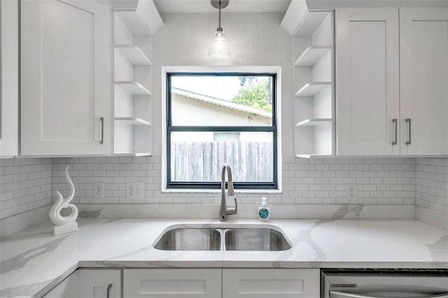 kitchen with white cabinetry, sink, pendant lighting, and light stone counters