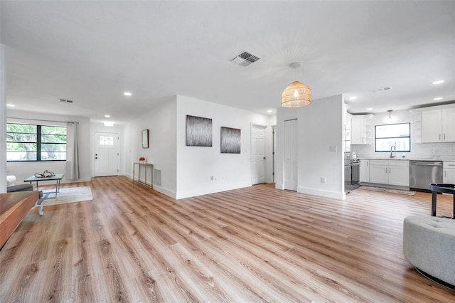 unfurnished living room with sink and light hardwood / wood-style flooring