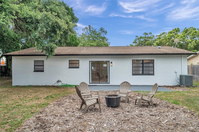 back of property with a yard, central AC unit, and a fire pit