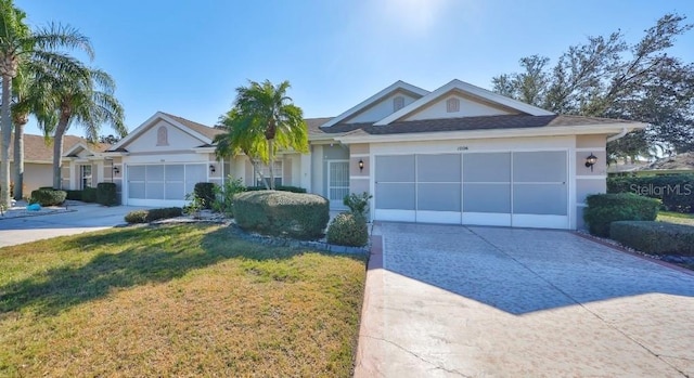 single story home featuring concrete driveway, a front lawn, an attached garage, and stucco siding