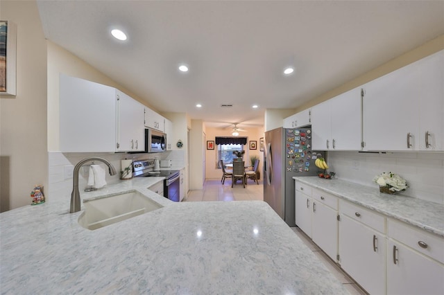 kitchen with tasteful backsplash, white cabinets, stainless steel appliances, a sink, and recessed lighting