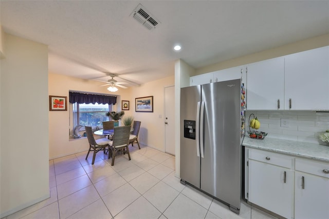 kitchen featuring stainless steel fridge, visible vents, a ceiling fan, backsplash, and light tile patterned flooring