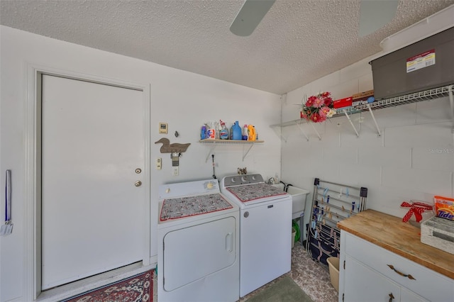 laundry room with concrete block wall, laundry area, ceiling fan, a textured ceiling, and washer and dryer