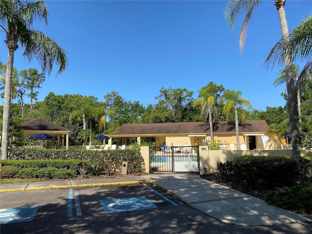 single story home with a gate, fence, uncovered parking, and stucco siding