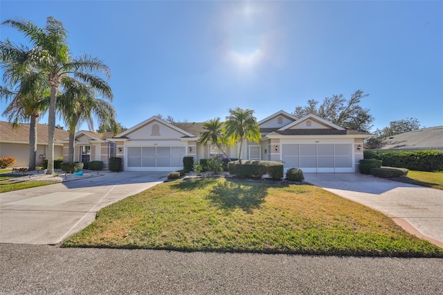 ranch-style home featuring a front lawn, concrete driveway, an attached garage, and stucco siding