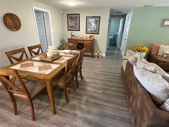 dining room featuring dark hardwood / wood-style flooring and a textured ceiling