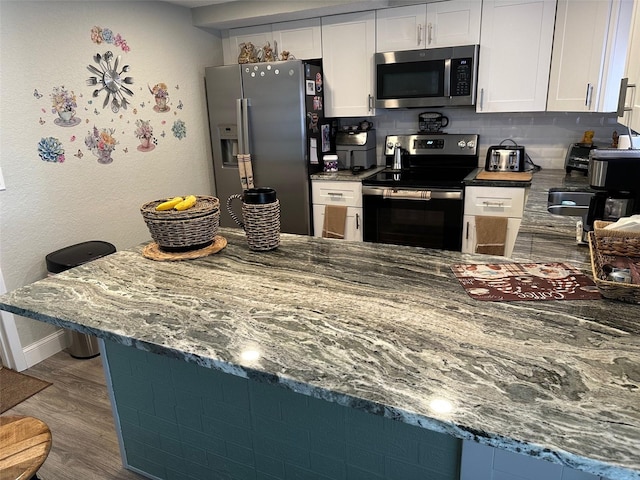 kitchen with stainless steel appliances, white cabinetry, dark wood-type flooring, and decorative backsplash