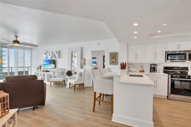 kitchen with sink, appliances with stainless steel finishes, a kitchen breakfast bar, white cabinets, and kitchen peninsula