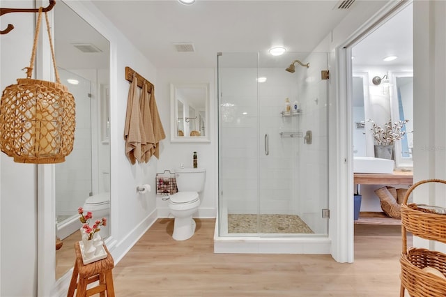 bathroom with hardwood / wood-style flooring, a shower with door, and toilet