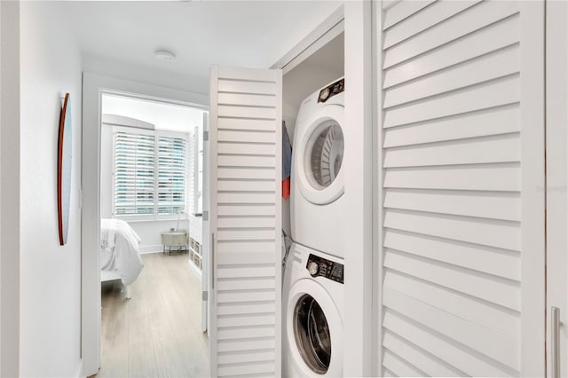 clothes washing area featuring stacked washer / drying machine and light hardwood / wood-style flooring