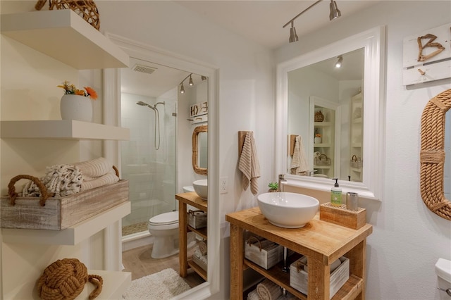 bathroom featuring built in shelves, toilet, sink, and a tile shower