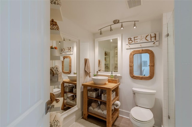 bathroom featuring toilet, sink, and rail lighting