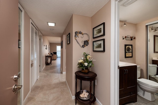 hallway featuring a textured ceiling and light tile patterned floors