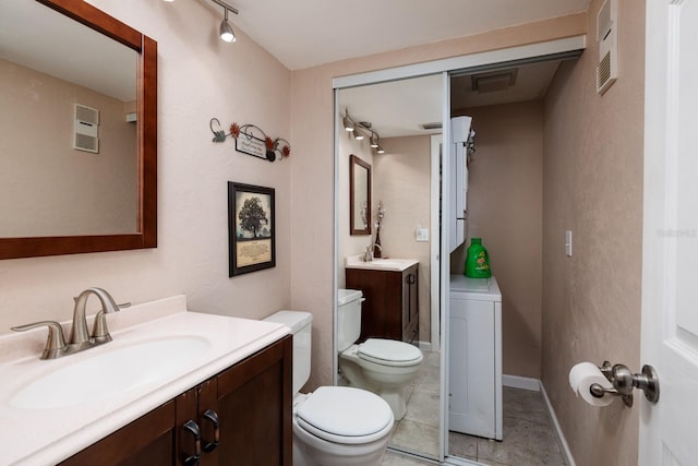 bathroom with toilet, track lighting, vanity, washer / clothes dryer, and tile patterned flooring