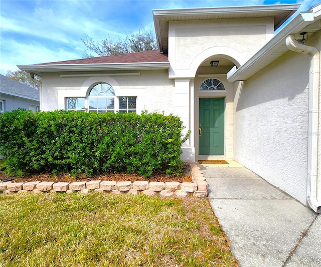 property entrance with a lawn