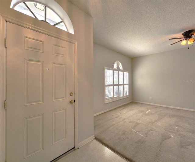 entryway featuring light carpet, ceiling fan, and a textured ceiling