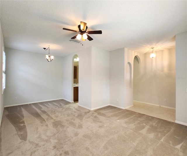 carpeted spare room featuring ceiling fan with notable chandelier and a textured ceiling