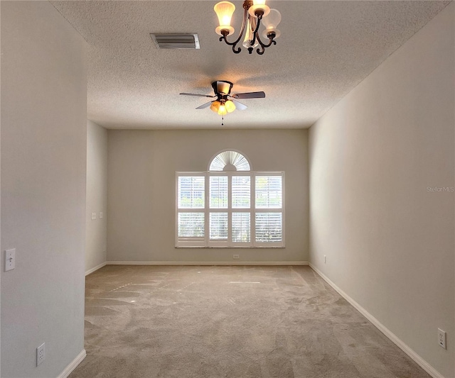 empty room featuring ceiling fan with notable chandelier, light colored carpet, and a textured ceiling