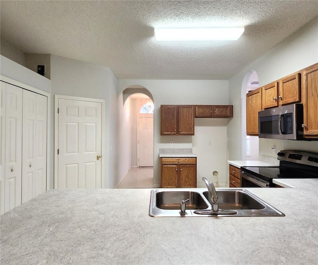 kitchen featuring sink, stainless steel appliances, and a textured ceiling