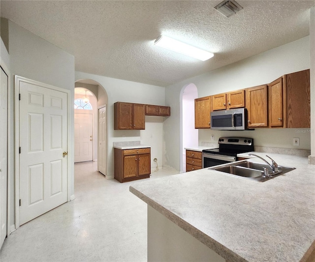 kitchen with stainless steel appliances, kitchen peninsula, sink, and a textured ceiling